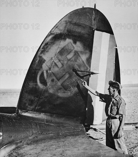 Collaboration between vichy and axis powers, the tail of a German aircraft damaged at Palmyra with Vichy markings painted over with the nazi Swastika.