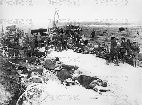 Casualites from world war one on stretchers in the battle field waiting to be evacuated, red cross and vehicle support waiting to transport them.