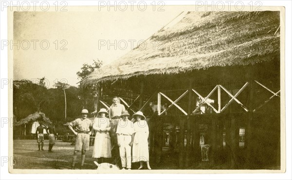 The Tamlins outside a thatched building