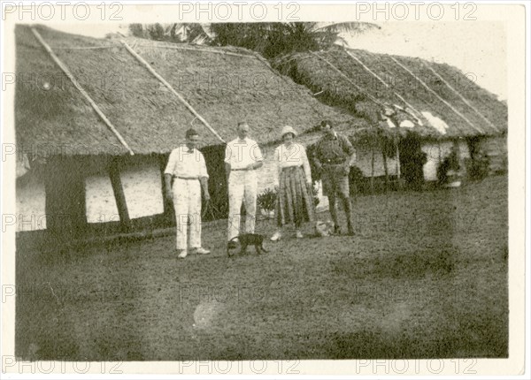 Dorothy Tamlin outside thatched houses