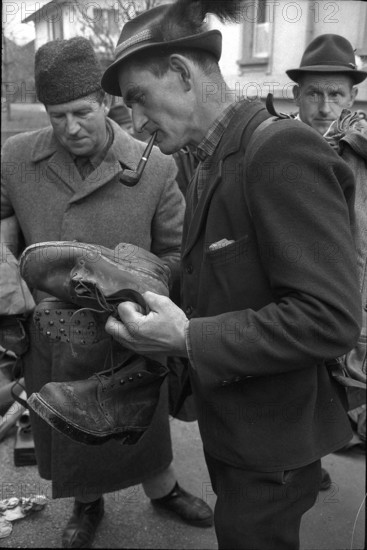 Thun, selling of disused army equipment, man examining shoes; 1969.