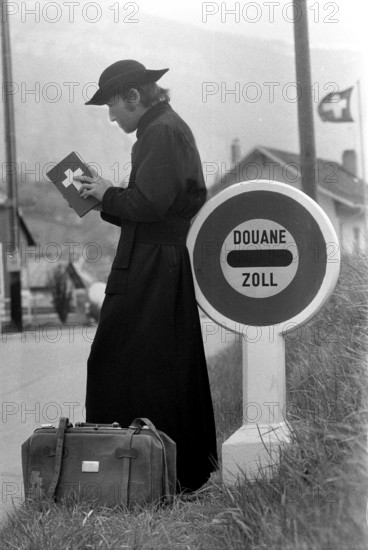Jesuit leaning on customs sign, 1973