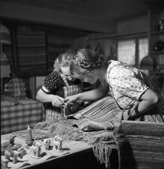Women examining rag rugs, 1940