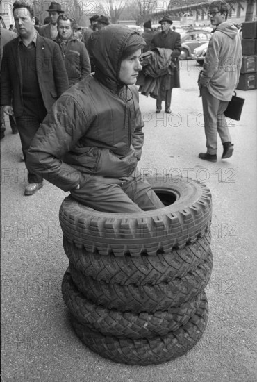 Thun, sale of used army equipment, young man with car tires; 1969