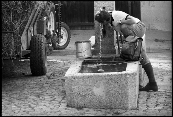 Hiker drinking water at a fountain, Switzerland 1971