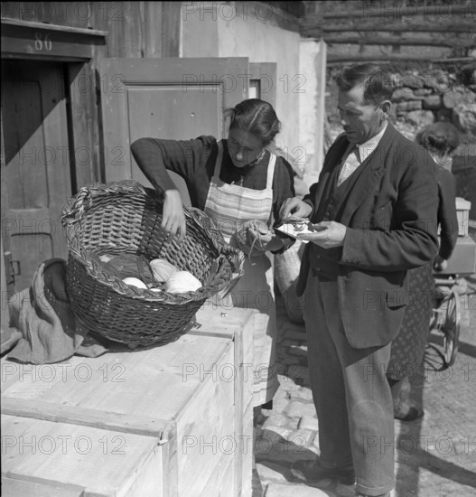 Woman examining scraps of fabric for rag rugs, 1940