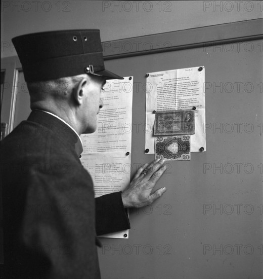 Official reads notice about counterfeit banknotes in circulation; 1943