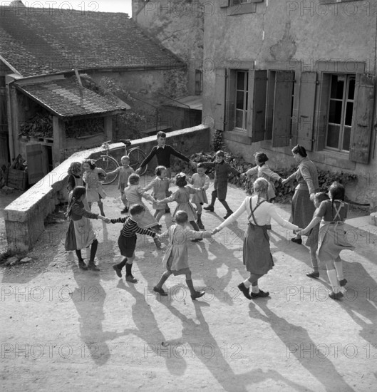 Coinsins; Teacher Elisabeth Glauser and her class playing ringaringaroses; 1949