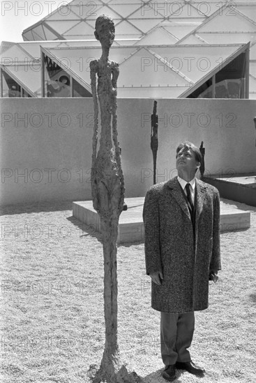 Man beside sculpture of Giacometti; Expo 1967.