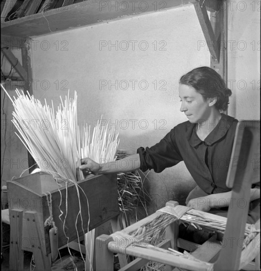 Woman braiding straw around a chair, 1940.