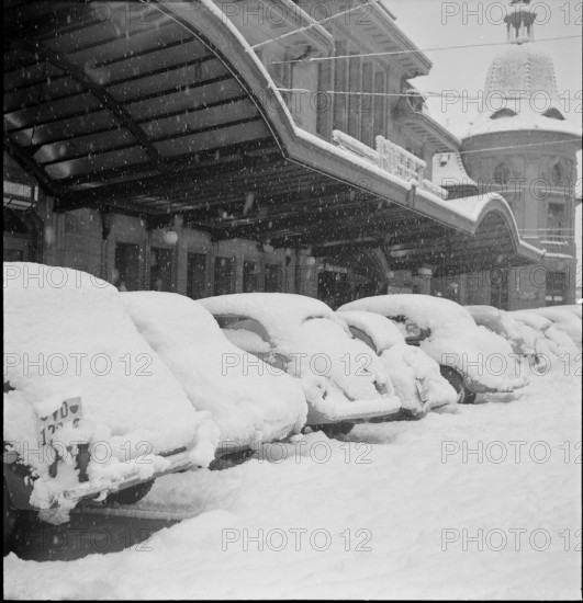 Snowfall in Lausanne: snowy cars in front of the railway station; 1952.