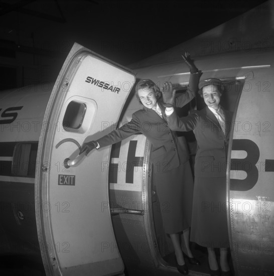 Swissair hostesses waving out of airplane door 1953.