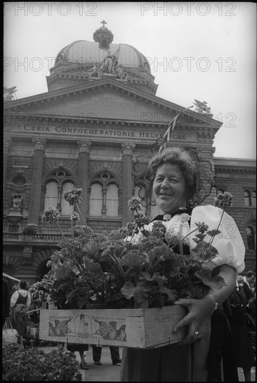 Woman with geranium in front of parliament building, Berne 1966.