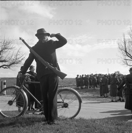 Civilian marksman with bicycle looking at female soldiers, Weinfelden 1954.