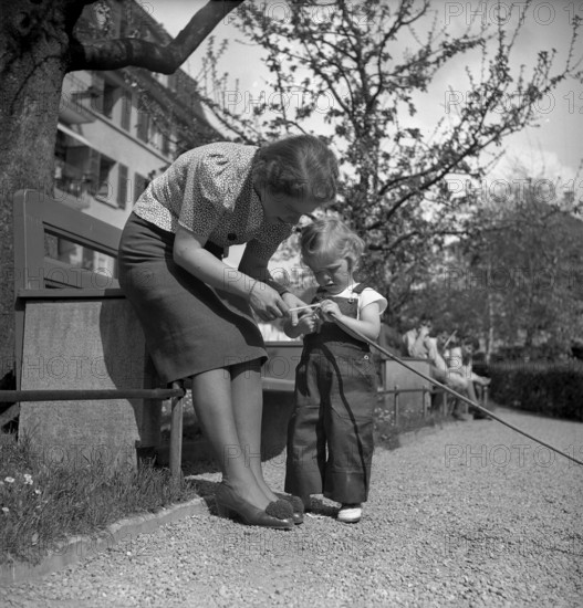 Mother and daughter playing outdoors, Switzerland 1940.