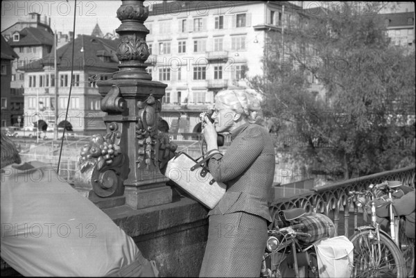 Tourist takes a photo on Muenster bridge in Zurich, 1962.