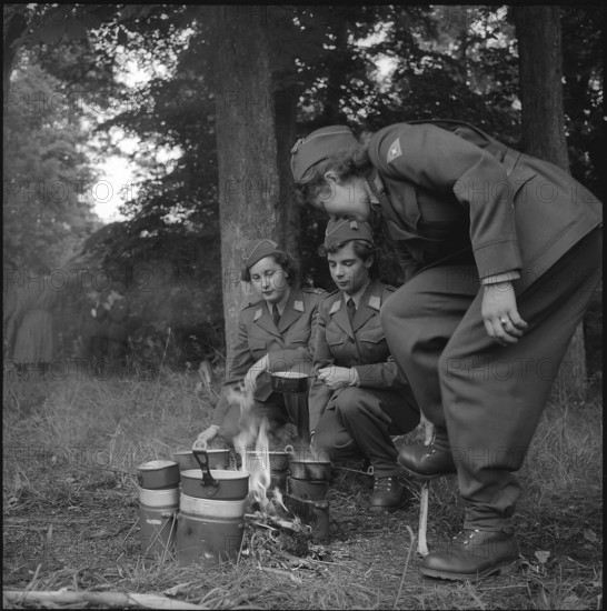 Women soldiers preparing meal at open fire, Fribourg 1962.