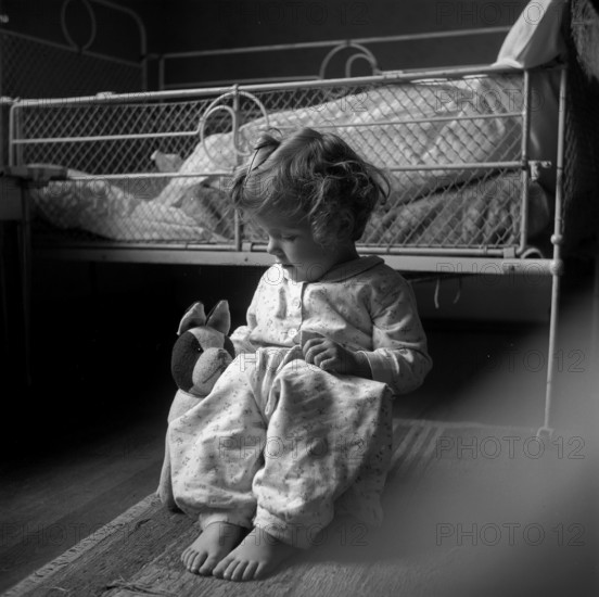 Girl sitting on the floor in front of her bed, Switzerland 1940.