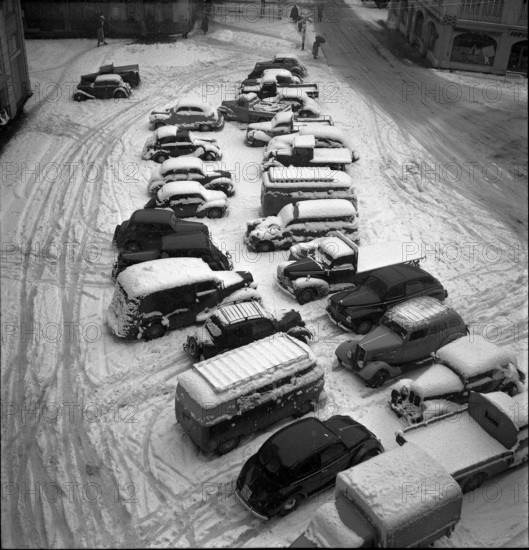 Snowfall in Lausanne: snow-covered cars on car park; 1952.