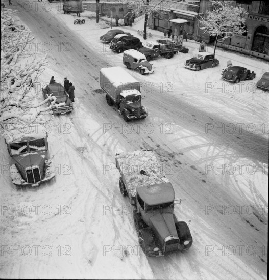 Snowfall in Lausanne: Trucks driving on a snowy street; 1952.