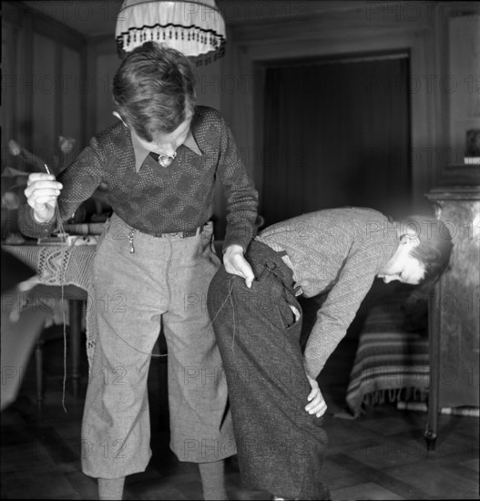 Boy mending his brother's trousers on Mother's Day, 1941.