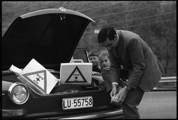 Man cares for foot injury with first aid case in his car 1970.