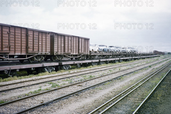 Railway train freight wagons and cars being transported by train piggyback transporter, Australia 1956 due to differing rail gauges.