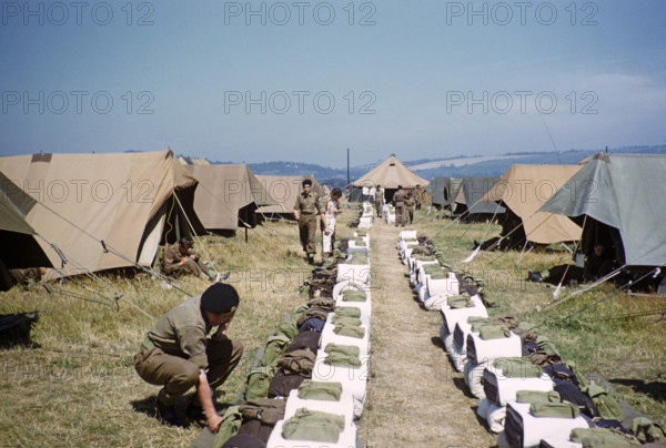 Schoolboys engaged in military training exercises as army cadets, southern England, UK, late 1950s boys lining up kit for inspection in front of their tents at campsite.