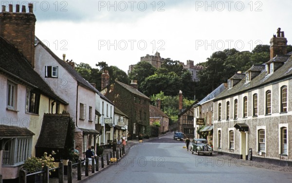 Dunster castle and historic buildings, main village street, High Street, Dunster, Somerset, England, UK early 1960s.