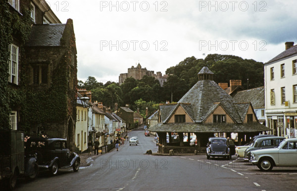 Dunster castle and Yarn Market building, main village street, High Street, Dunster, Somerset, England, UK early 1960s.