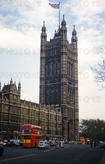 Red double-decker buses passing Westminster Abbey church,  London, England, UK 1962.