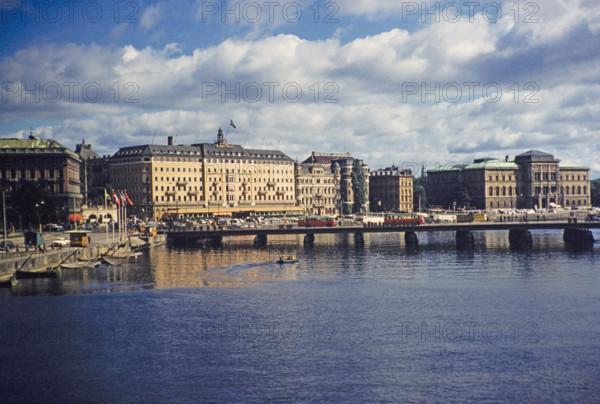Buses crossing Strombron bridge in city centre with Grand Hotel and National Museum buildings behind, Stockholm, Sweden 1958.