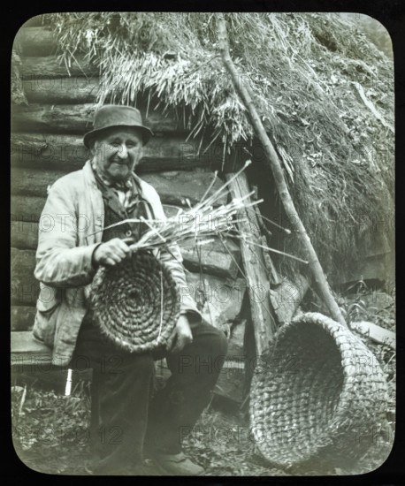 Portrait of elderly countryman weaving straw baskets in England, c 1890s-1900.