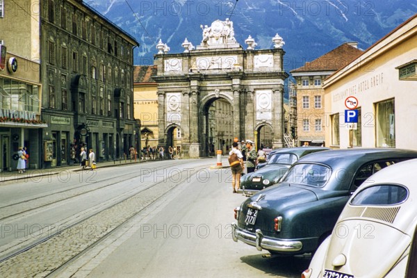 Triumphal arch in Maria-Theresien-Strasse street city centre of Innsbruck, Austria, Europe 1950s - cars parked outside Hotel Greif.