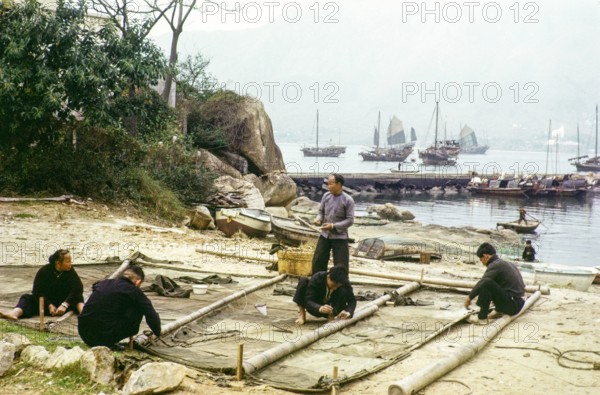 People on beach repairing their junk boat sail, Castle Peak, New Territories, Hong Kong, Asia, 1964.
