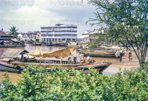 Unloading sacks from cargo boat on Singapore River, Singapore, southeast Asia c 1963 Sime Darby Ltd Godown warehouse  in background.