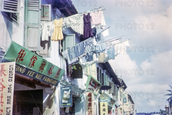Laundry held out on poles to dry above Chinese shops in  Singapore, south east Asia, 1965.
