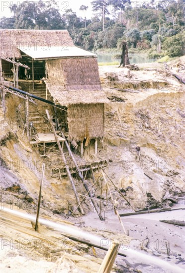 Open Cast gravel-pumping tin mine Malaya, Malaysia, south east Asia 1964 -  pumping raises the slurry from the sump to an elevated wooden sluice level called a palong.