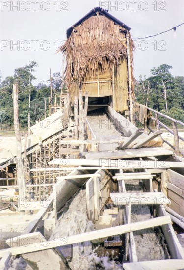 Open Cast gravel-pumping tin mine Malaya, Malaysia, south east Asia 1964 - pumping raises the slurry from the sump to an elevated wooden sluice level called a palong.