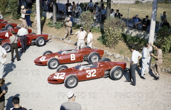 Ferrari Formula One team in  paddock  with sharknose Ferrari 156 F1 cars, Ferraris, Monza Grand Prix, Italy 1961 thought to be Baghetti  chatting with a mechanic right side.