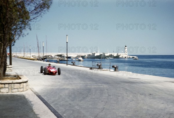 Formula One motor racing Monaco Grand Prix race 1961, Richie Ginther in Ferrari 156 F1 sharknose car approaching tobacconist kiosk.