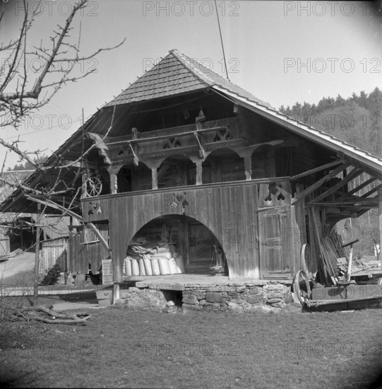 Man bundling firewood in front of a granary in Wynigen BE 1960