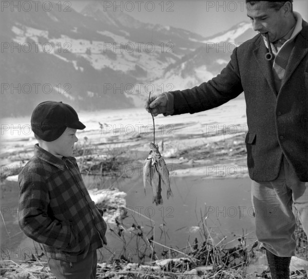 A fisherman showing fish to a boy, Seewen SZ 1965