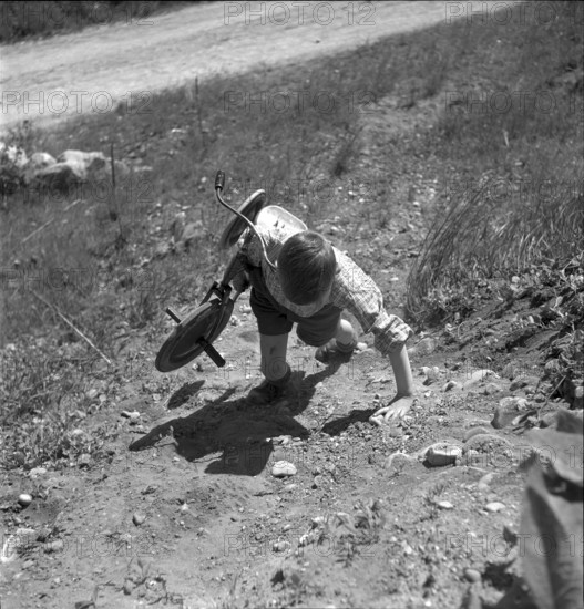 Muntelier, boy carrying his tricycle, 1950