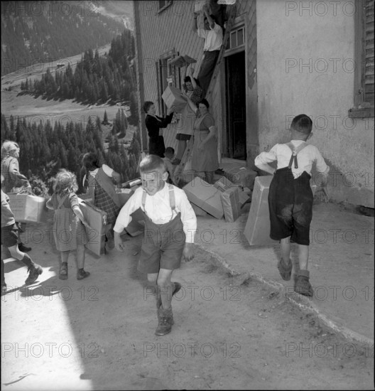 Children carrying parcels, relief supplies for the population of the completely burned down hamlet Selva 1949