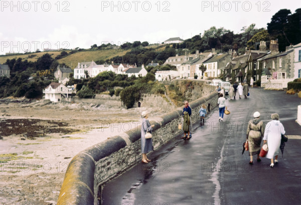 People walking on coastal promenade road.