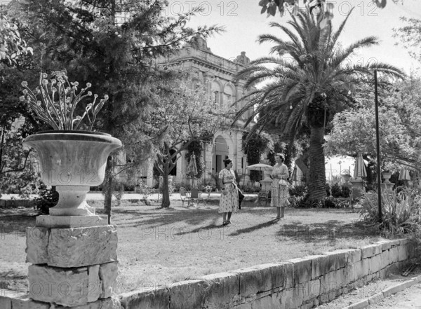 Two women standing in garden of Baroque style classical building at unknown location in Malta.