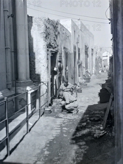 Workers with metal pots in narrow alleyway street in old town medina.