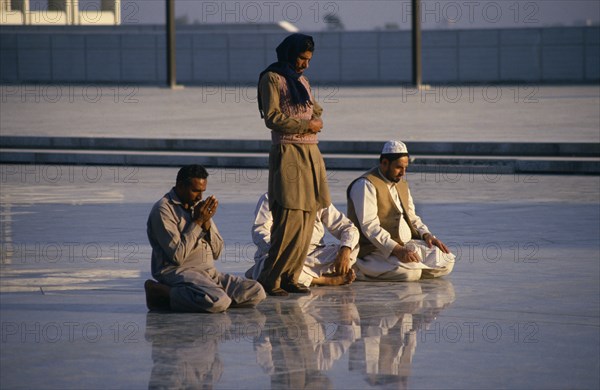 PAKISTAN, Islamabad, "Faisal Mosque. Four men at prayer, reflected in surface of  shiny marble floor."
