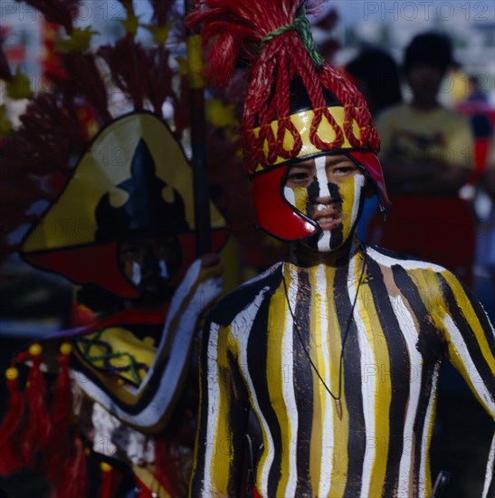 PHILIPPINES, Luzon, Manila, Boy at Ati-Atihan  festival with striped painted body and wearing a red headdress